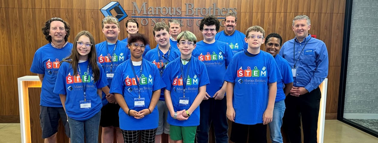 Students and adults standing in front of the Marous Brothers sign