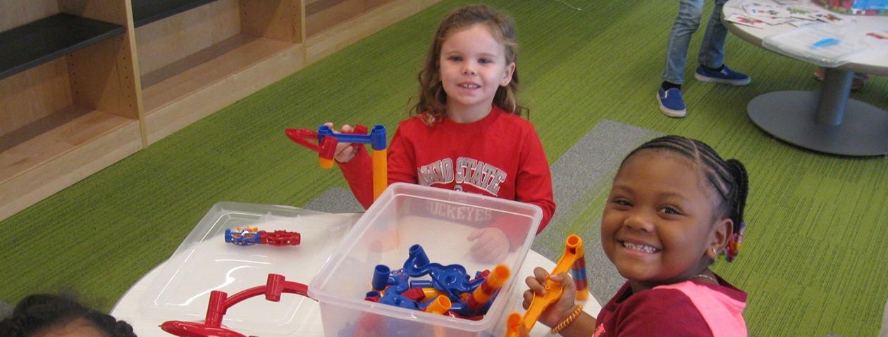 two girls smiling building marble runs