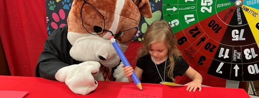Girl writing on paper with person in a dog costume