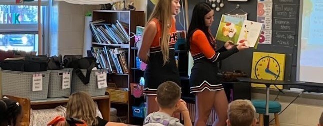Two high schoolers reading to elementary class