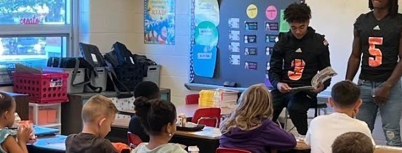 Two highschool students reading to elementary class