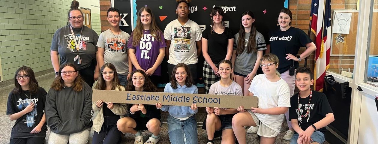 Eastlake Middle School students holding a sign of the school&#39;s name because they were awarded a new Buddy Bench by the Fair Housing Resource Center